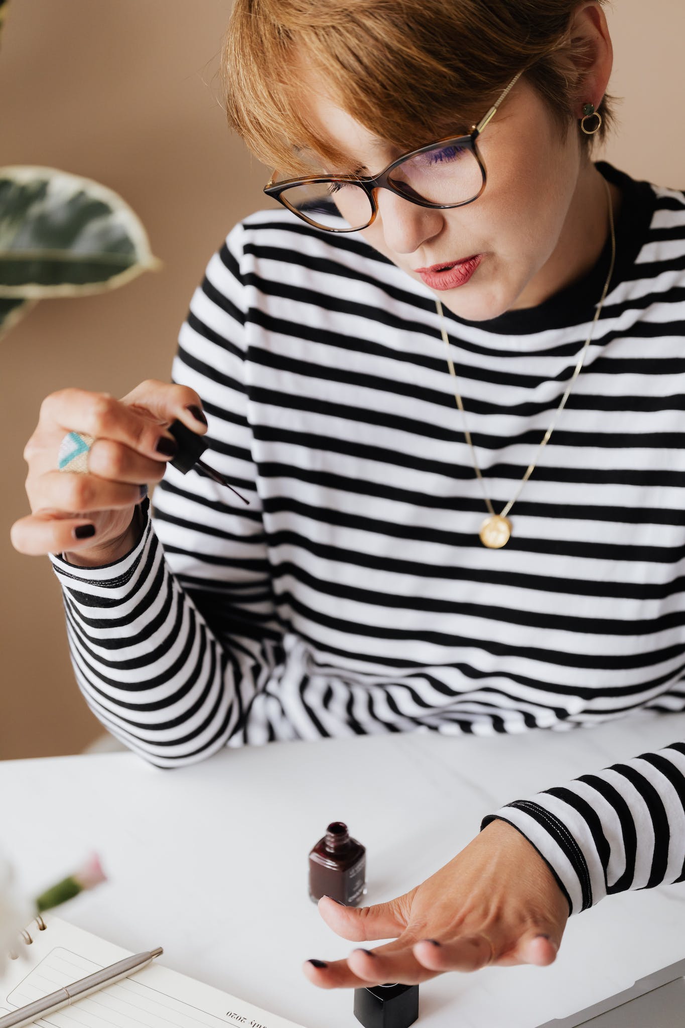 Young woman in glasses polishing nails at home